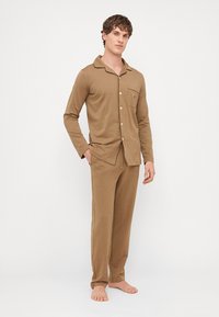 Braunes Schlafanzug-Set aus weichem Stoff, bestehend aus einem langärmeligen Hemd mit Kragen und Knöpfen sowie passenden Hosen. Keine Muster oder Akzente.