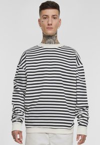Svart og hvit stripete langermet genser med crew neckline og ribbestrikkede mansjetter. Laget av et mykt, teksturert stoff. Komfortabel passform.