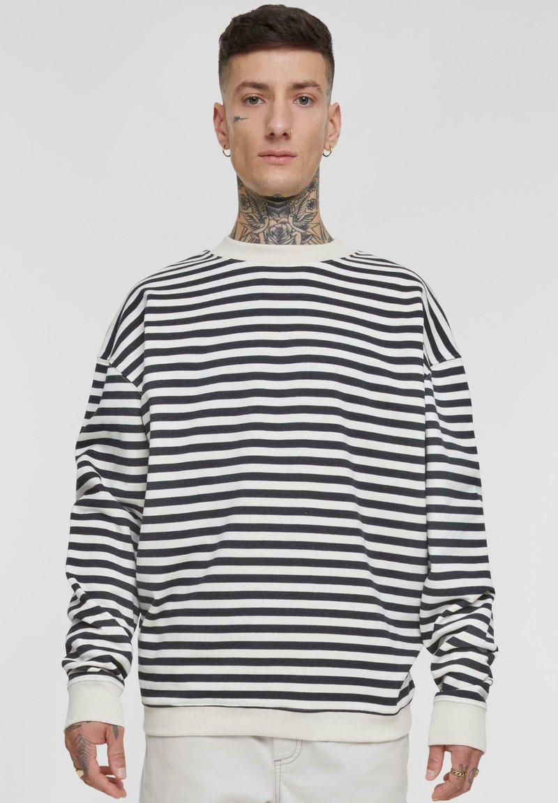 Svart og hvit stripete langermet genser med crew neckline og ribbestrikkede mansjetter. Laget av et mykt, teksturert stoff. Komfortabel passform.