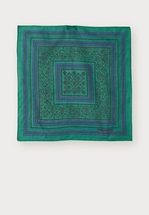 Écharpe verte avec des motifs floraux noirs complexes, bordée de lignes bleues et violettes. Tissu léger, de forme carrée, avec un logo imprimé.