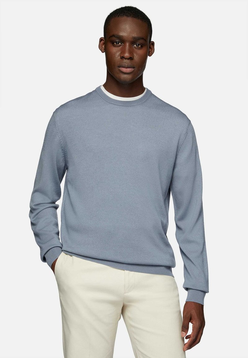 Light blue ribbed sweater with a crew neckline, long sleeves, and a subtle texture, paired with cream-colored trousers.