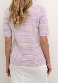 Top de punto a rayas pastel con mangas cortas, que presenta un diseño texturizado y acentos decorativos de tejido abierto. Falda blanca visible en la parte inferior.