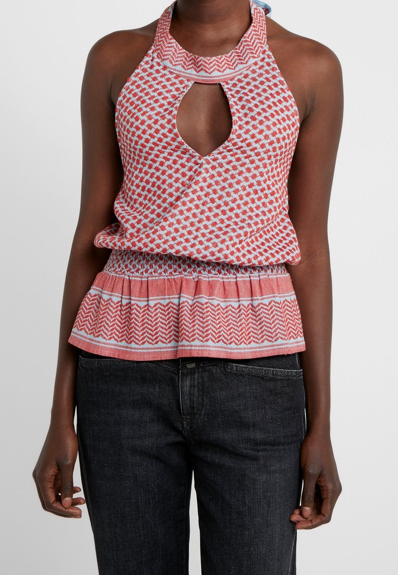 Red and white patterned halter top with a keyhole neckline and peplum hem. Soft fabric with a smocked waist detail.