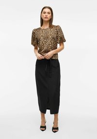 Gornji dio sa leopard uzorkom i puf rukavima, uparen s crnom suknjom koja ima prorez sprijeda i detalj u obliku vezivanja u struku. Glatke teksture u cijelosti.