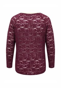 Haut en dentelle bordeaux à manches longues avec motif floral, tissu semi-transparent et encolure arrondie, vu de dos.