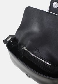 Borsa a mano in pelle nera con texture liscia, dotata di patta aperta, tasca interna con zip e chiusura con dettagli in metallo color argento.