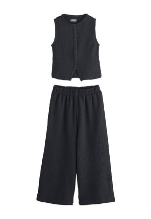 Haut sans manches noir texturé avec boutons, associé à un pantalon large assorti avec taille élastique, posé à plat sur fond blanc.