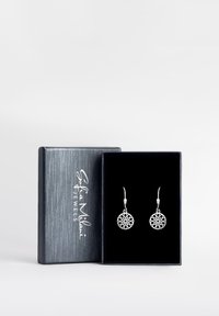 Silverörhängen med intrikata cirkulära utskärningar som hänger från krokar. Presenteras i en mörkblå sammetfodrad låda.