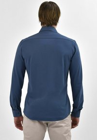 Langärmige shirt in blauwe stof met een gladde textuur. Heeft een kraag en knoopmanchetten, met een op maat gesneden pasvorm aan de achterkant.