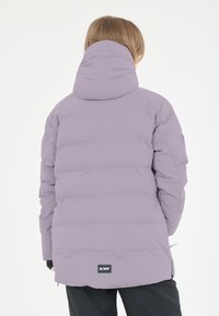 Puffjakke i lyse lavendel med horisontalt quiltet design, hætte og sort label i kanten. Glat, isoleret materiale.