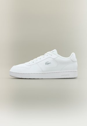 Weißer Low-Top-Sneaker mit Schnürung vorne, Lacoste Krokodil-Logo an der Seite und gebrandeter Sohle, auf neutralem Hintergrund dargestellt.