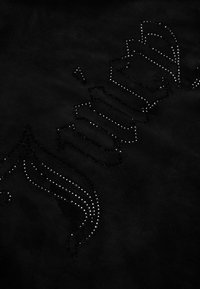 Černá tkanina s designem z hřebů tvořícím slovo v gotickém stylu písma a ozdobnými křídly po stranách.