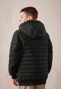 Giubbotto imbottito nero con design trapuntato orizzontale, cappuccio, polsini elastici e orlo a costine. Presenta una texture liscia e materiale leggero.