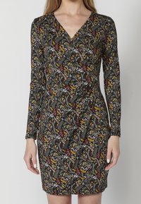 Czarna sukienka z długimi rękawami, dekoltem w kształcie litery V oraz kwiatowym wzorem w czerwonych, żółtych i białych akcentach. Gładki materiał o dopasowanej sylwetce.