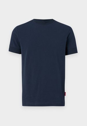 Sötétkék pamut póló rövid ujjakkal, kerek nyakkivágással, és egy kis piros címke díszítéssel az alsó bal szegélyén. Puha tapintású, egyszerű dizájn.