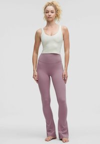 Világoszöld crop top és pasztell rózsaszín, bővülő leggings rugalmas anyagból, magas derékkal és sima, fényes felülettel.