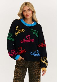 Czarny sweter robiony na drutach z kolorowym haftem "Amore" w odcieniach czerwieni, różu, zieleni, żółci i niebieskiego, z jasnoniebieskim kołnierzem oraz strukturalną tkaniną.
