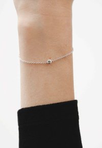 Pulsera de cadena de plata con una pequeña gema redonda y clara en el centro; diseño delicado con finos eslabones y acabado pulido.