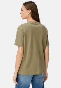 Oliwkowy t-shirt z krótkim rękawem, okrągłym dekoltem i lekko opadającymi ramionami. Wykonany z miękkiego materiału, charakteryzuje się minimalistycznym wzornictwem.