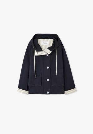 Chaqueta negra con capucha, botones blancos, dos bolsillos delanteros, cordones blancos y forro y puños a rayas crema.