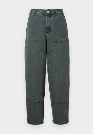 Denim hlače v temno modri barvi z ohlapnim krojem, ki imajo stranske žepke in kontrastno šivanje. Tkanina ima rahlo zbledel videz.