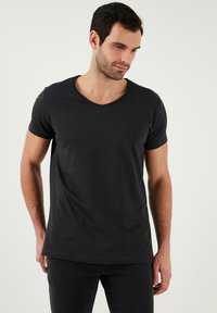 Fekete, rövid ujjú póló V-kivágással, puha anyagból készült. Laza illeszkedést és sima, egyenletes textúrát kínál.