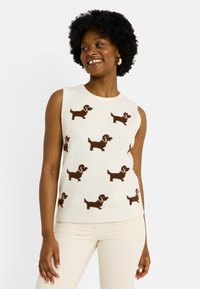 Un pull en tricot sans manches de couleur crème présentant un motif de teckel marron sur l'ensemble. Le design possède un col rond et une texture douce.