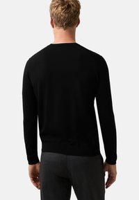 Czarny sweter dzianinowy z długimi rękawami, okrągłym dekoltem oraz ściągaczami przy mankietach i u dołu. Gładka tekstura, dopasowany krój, bez widocznych wzorów ani akcentów.