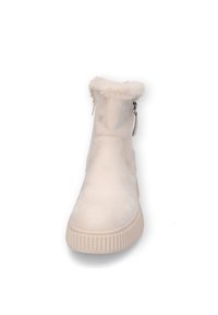 Helle beige Ankle Boots aus Wildleder mit einem pelzigen Kragen, seitlichem Reißverschluss und strukturiertem Gummisohle mit horizontalen Rillen.