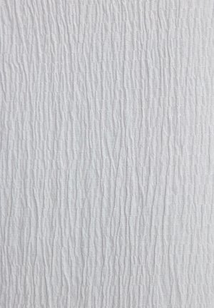 White textured fabric with a rippled pattern, featuring vertical lines of varying thickness, creating a wavy appearance throughout.