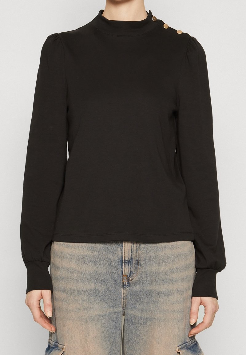 Schwarzes Langarmshirt mit hohem Kragen, mit gerafften Schultern und drei goldenen Knopfakzenten auf der linken Schulter. Glattes Material.