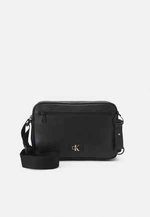 Borsa a tracolla rettangolare nera con tracolla regolabile, tasca frontale con zip e piccolo logo di Calvin Klein.
