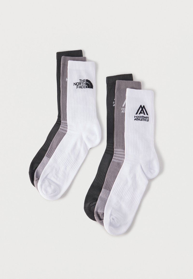 Δύο σετ από τρεις ριμπ βαμβακερές κάλτσες σε μαύρο, γκρι και άσπρο, με λογότυπα The North Face και Mountain Athletics στις λευκές κάλτσες.