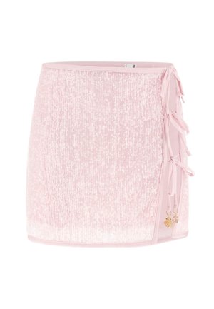 Jasnoróżowa mini spódniczka z cekinami, z wiązaniami po bokach oraz małymi złotymi zawieszkami muszelki i półksiężyca na białym tle.