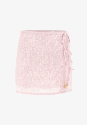 Jasnoróżowa mini spódniczka z cekinami, z wiązaniami po bokach oraz małymi złotymi zawieszkami muszelki i półksiężyca na białym tle.