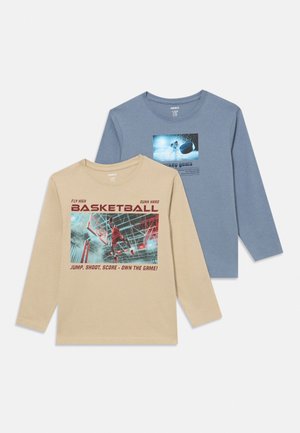 Deux chemises à manches longues, beige avec un graphisme de joueur de basketball et texte rouge, bleu avec un graphisme de joueur de hockey sur glace et palet, toutes deux à col rond.