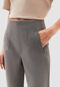 Pantalones ajustados grises con textura vertical, cintura alta y bolsillos laterales. La tela es suave con detalles sutiles en la parte delantera.