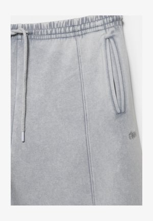 Világosszürke szabadidőnadrág elasztikus derékpánttal, zsinórral, oldalzsebekkel és finom hímzett logóval a zseb közelében.