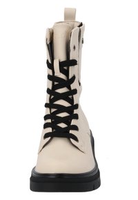 Bota de combate color crema con cordones negros y suela de goma; presenta una puntera redondeada y una cremallera lateral para facilitar su uso.