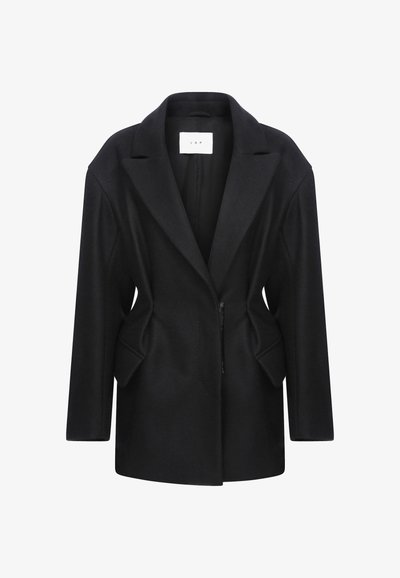 Musta villasekoitekangas takki, jossa on lovettu kaulus, yksittäinen vetoketjusuljin ja muotoiltu vartalo, jossa on sivutaskut.