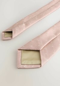 Rosa textile Riemen mit weißen Polka Dots und einem strukturierten, hellbeigen Futter, ausgestattet mit spitzen Enden. Glatte Stoffoberfläche insgesamt.