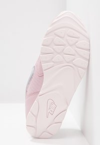 Vaaleanpunaiset sneakerit, joissa on verkkokangasta ja nahkaa, varustettuna urheilullisella kumipohjalla, jossa on kolmioita muistuttavia kuvioita ja näkyvä logo.