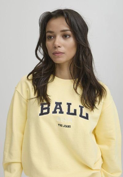 Sárga crewneck pulóver "BALL 1924 THE JEANS" felirattal sötétkék színben. Puha anyagból készült, laza szabású, bordás mandzsettákkal és hem elemmel.