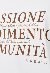 Weißes Shirt mit auffälligem braunem Text. Der Text enthält Phrasen zu Mode und Kultur. Das Shirt hat ein lässiges Design und eine glatte Textur.