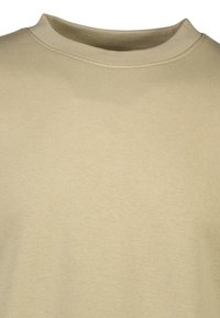 Camiseta de algodón beige con escote redondo y ribete acanalado. Textura suave, tejido ligero y diseño simple sin patrones ni acentos.