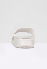 Sandale blanche à semelle texturée, à dos ouvert et au design minimaliste. Dispose d'un dessus lisse avec des découpes latérales pour la ventilation.