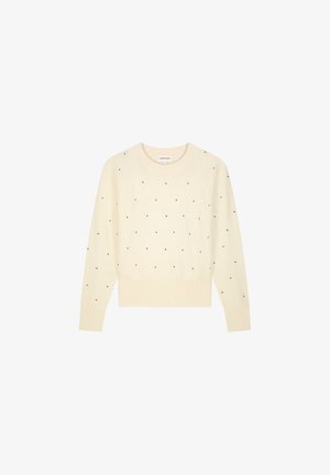 Crème kleurige trui met ronde hals, lange mouwen en een textuur in de brei. Versierd met verspreide zwarte stippen voor visuele accenten.