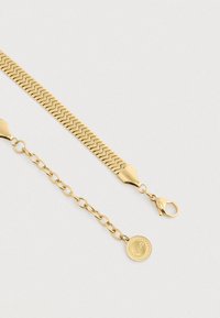 Gul kædearmbånd med et fiskeaksedesign, præget af en lobster-lås og en justerbar længde med en rund charme i enden.