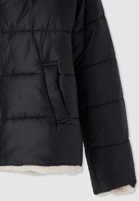 Giacca imbottita nera con design trapuntato orizzontale, una tasca laterale e una morbida fodera in pile sull'orlo. Materiale esterno liscio.