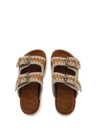 Bruna mockaskinnsandaler med två justerbara spännen, med vävda detaljer längs remmarna och en vadderad sula. Texturerad vit sula.